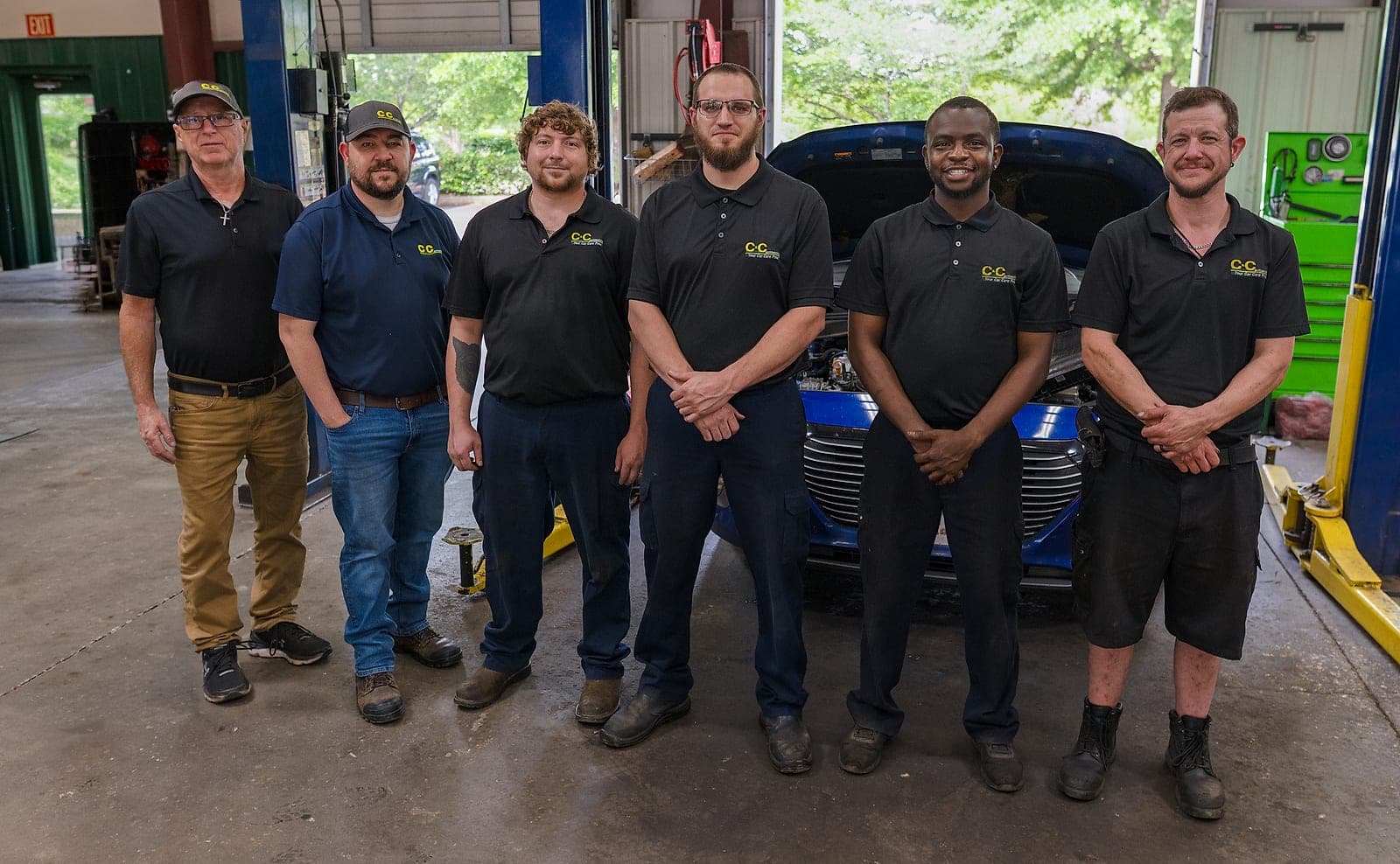 The C&C Automotive Aiken technicians lined up across the open service bays, with a vehicle on the lift behind them.
