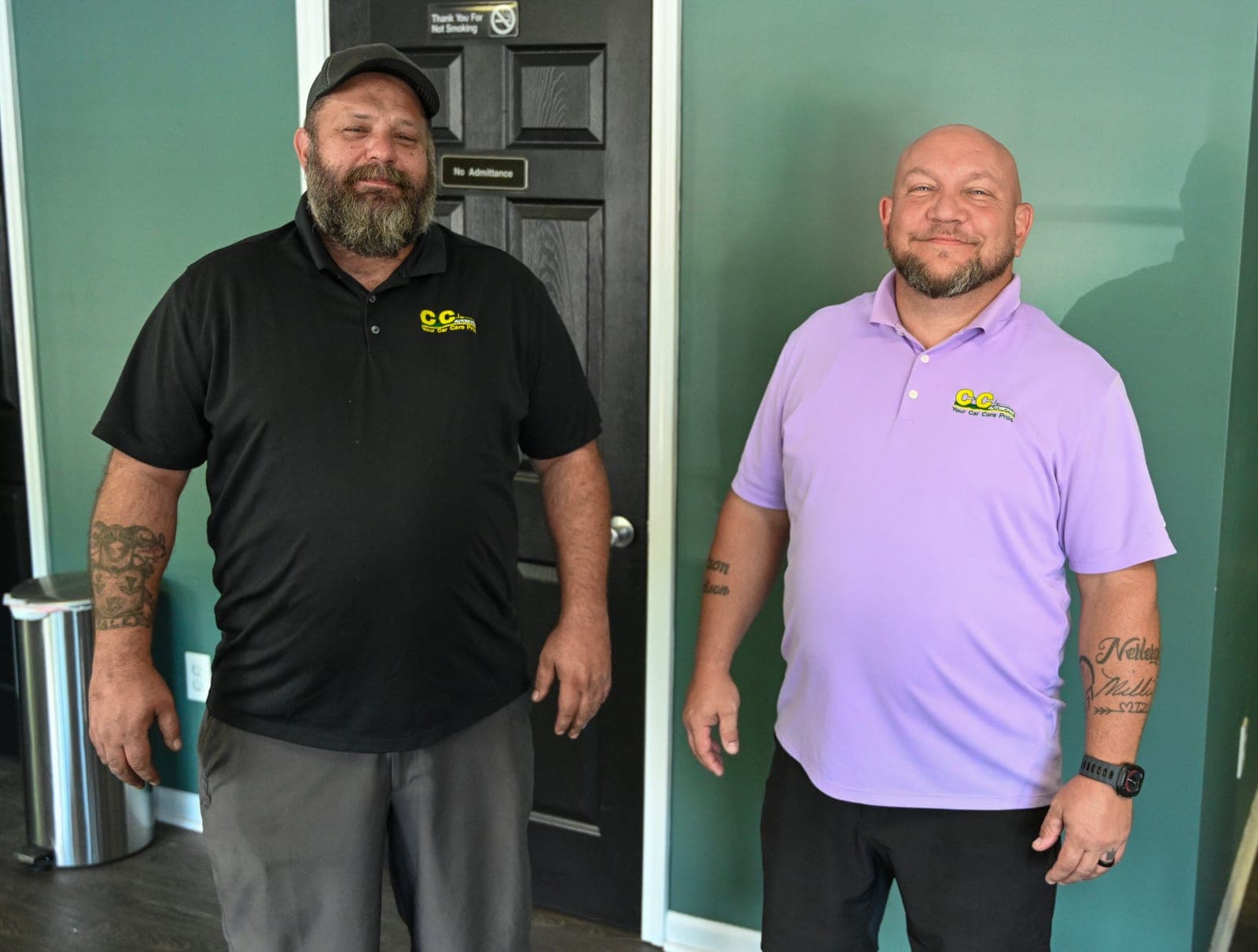 Two smiling members of the C&C Automotive Warrenville team in their shop polos, ready to greet customers in the front office.