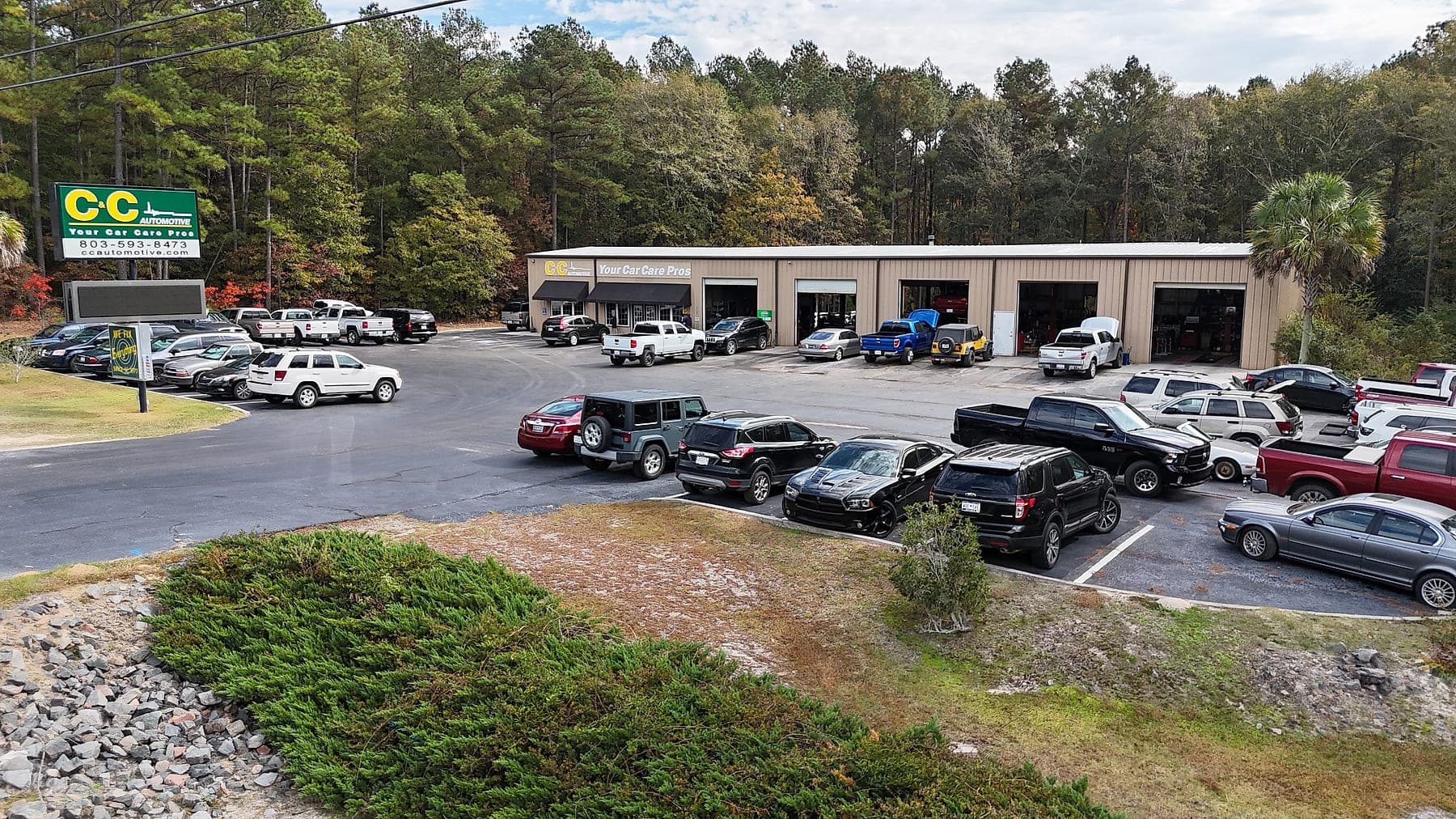 Aerial view of the C&C Automotive Warrenville shop on Jefferson Davis Highway, with multiple bay doors open and customer vehicles in the lot.