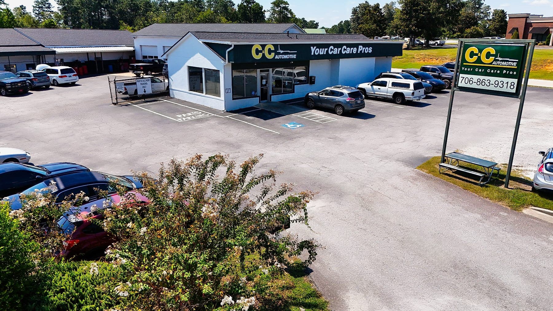 Aerial drone view of the C&C Automotive West Augusta shop on Wrightsboro Road, showing the front entrance and customer parking.