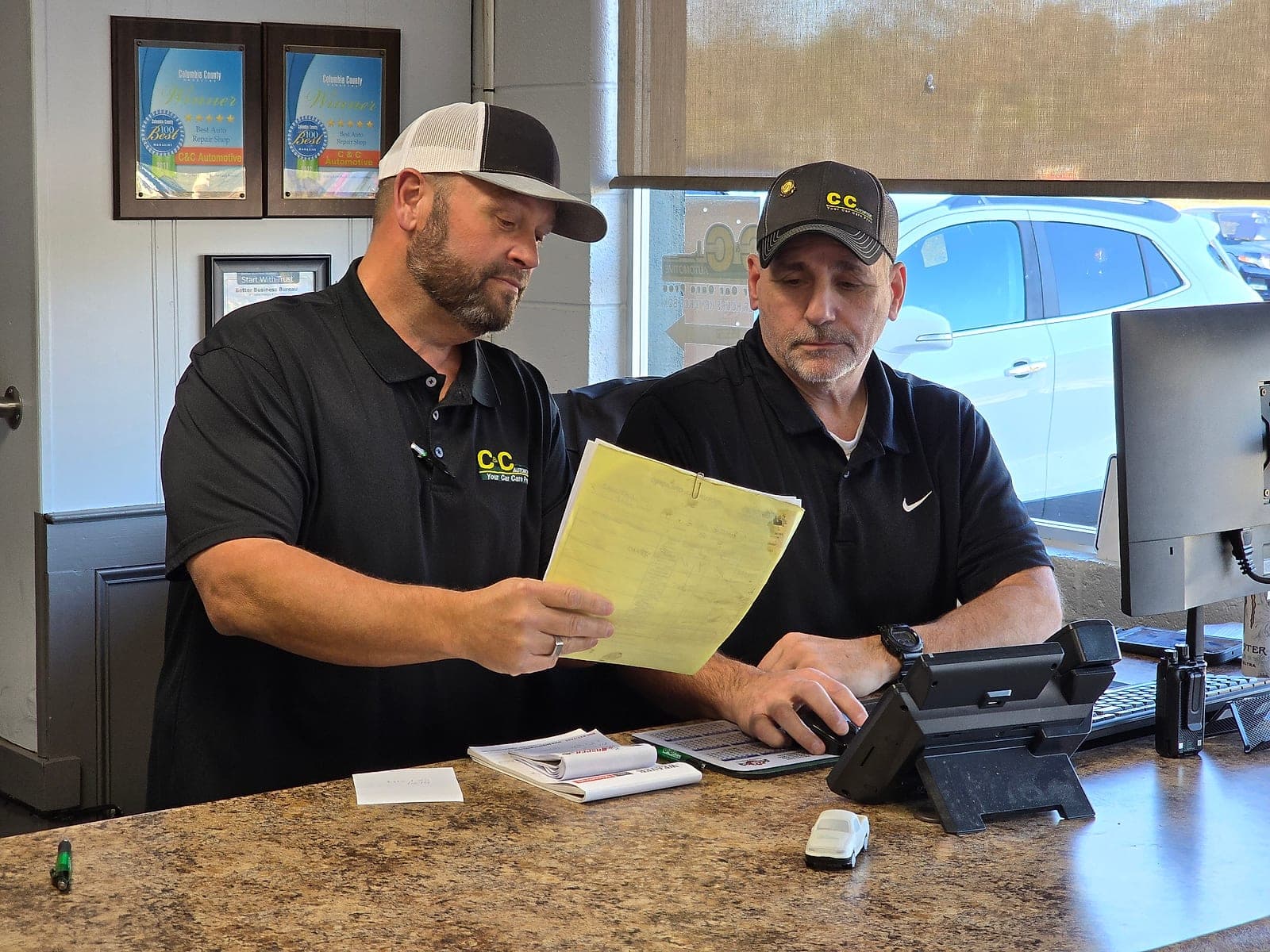 Two C&C Automotive service advisors going over a repair order together at the West Augusta front counter.