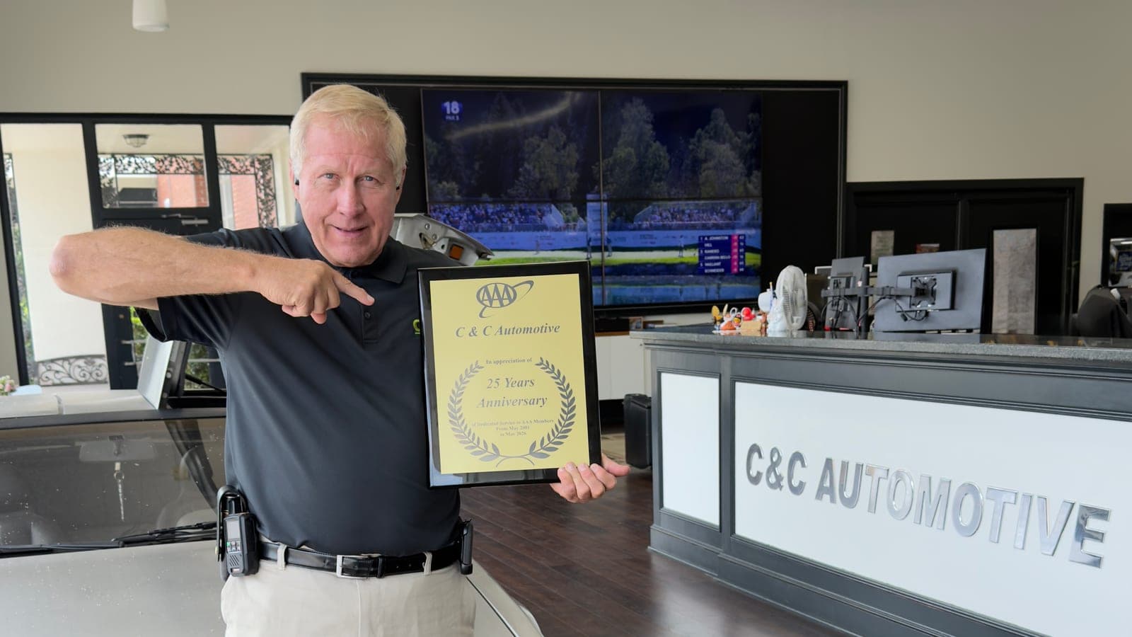 C&C Automotive owner holding the AAA 25 Years Anniversary plaque in the Downtown Augusta showroom