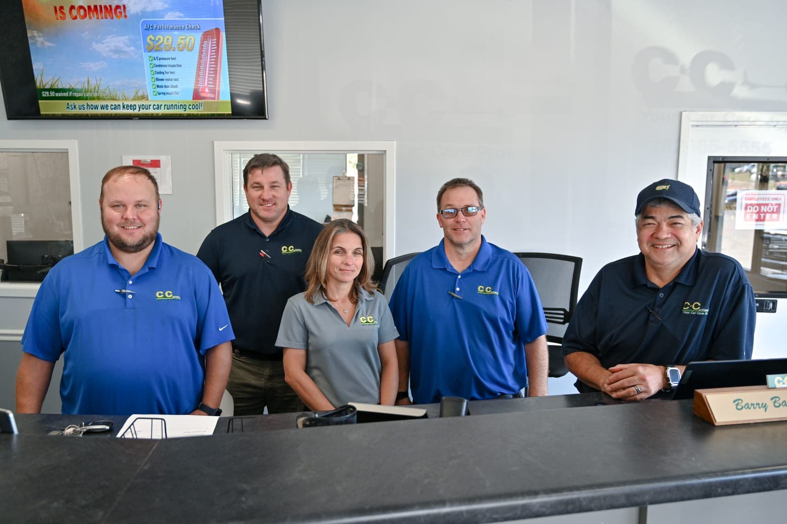 Five members of the C&C Automotive Martinez team smiling behind the shop's front counter